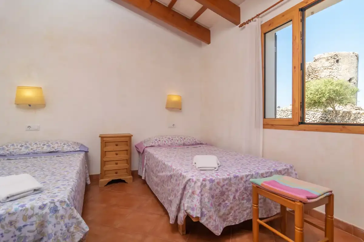 Dormitorio con dos camas y una ventana con vistas a una torre de piedra.