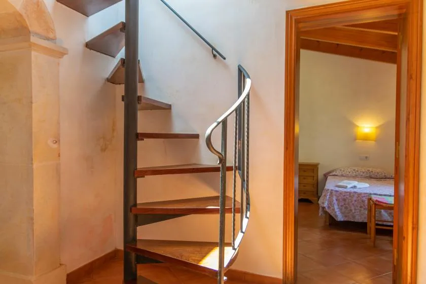 Una escalera de caracol está junto a una puerta abierta que da a un dormitorio.