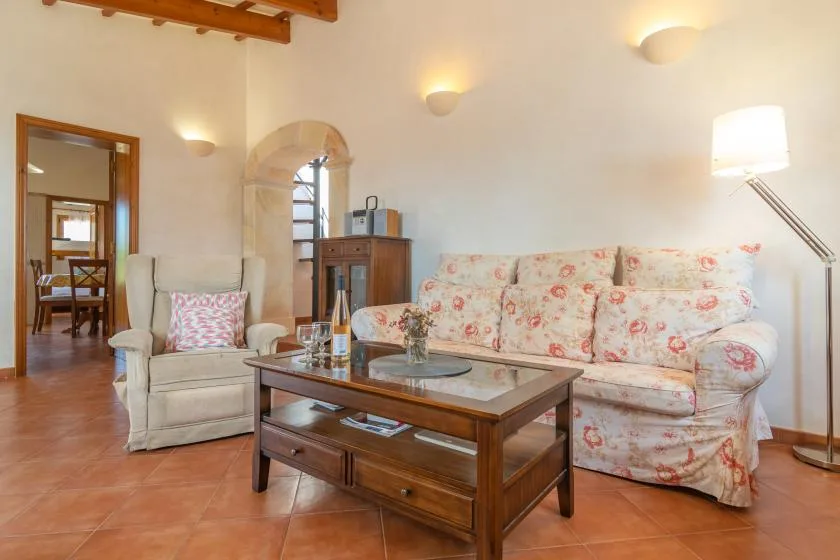 Una sala de estar con asientos florales, una mesa de centro y una lámpara de pie.