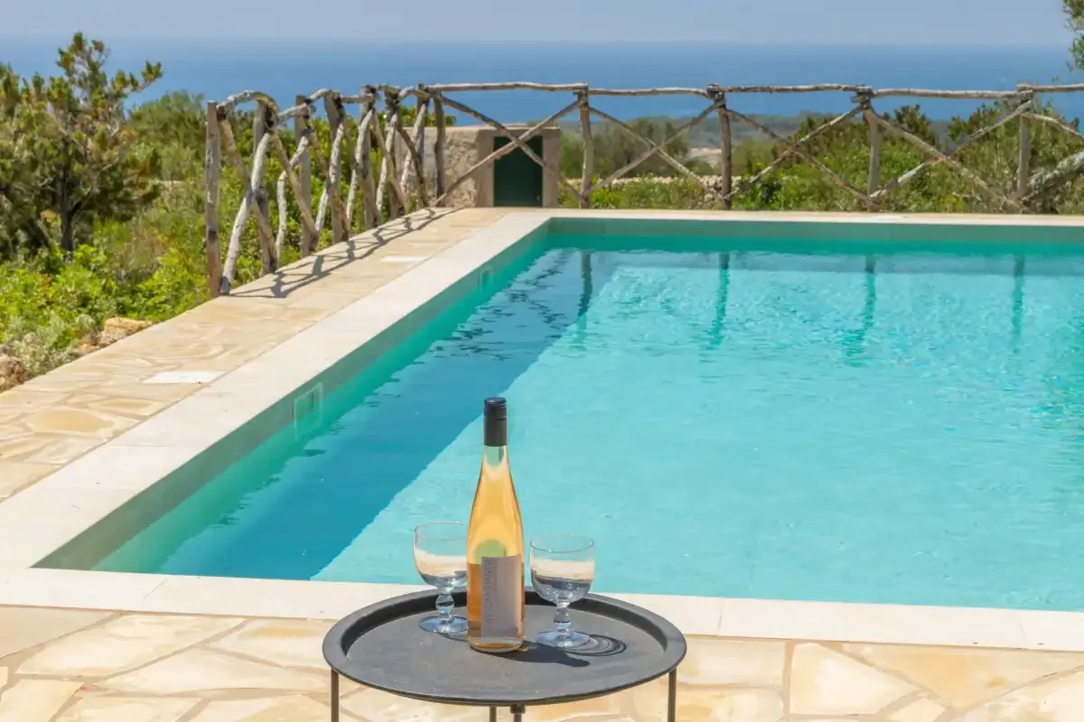 Una piscina con una mesita y bebidas junto al agua.