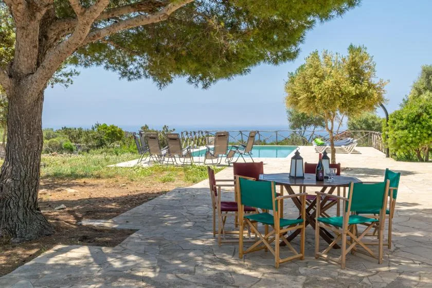 An outdoor dining area with a table and chairs beside a swimming pool.