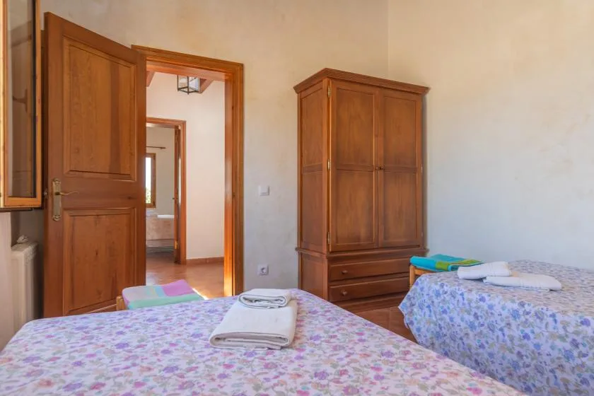 Un dormitorio con dos camas, armarios de madera y toallas dobladas.