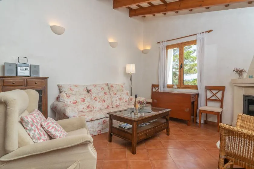 Una sala de estar con asientos florales, una mesa de centro de madera y una ventana.