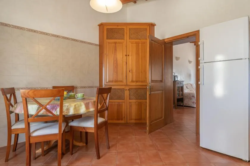 Comedor con una mesa de madera y sillas junto a un armario alto.