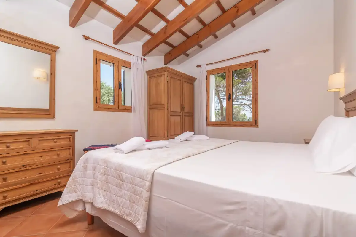 Dormitorio con dos camas, muebles de madera y vigas vistas en el techo.