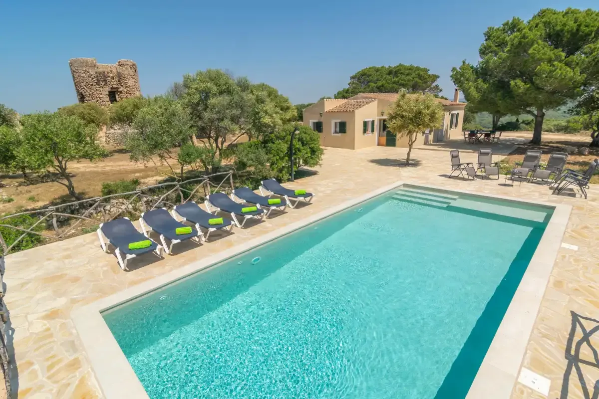Una piscina al aire libre con asientos de descanso junto a un edificio bajo y árboles.