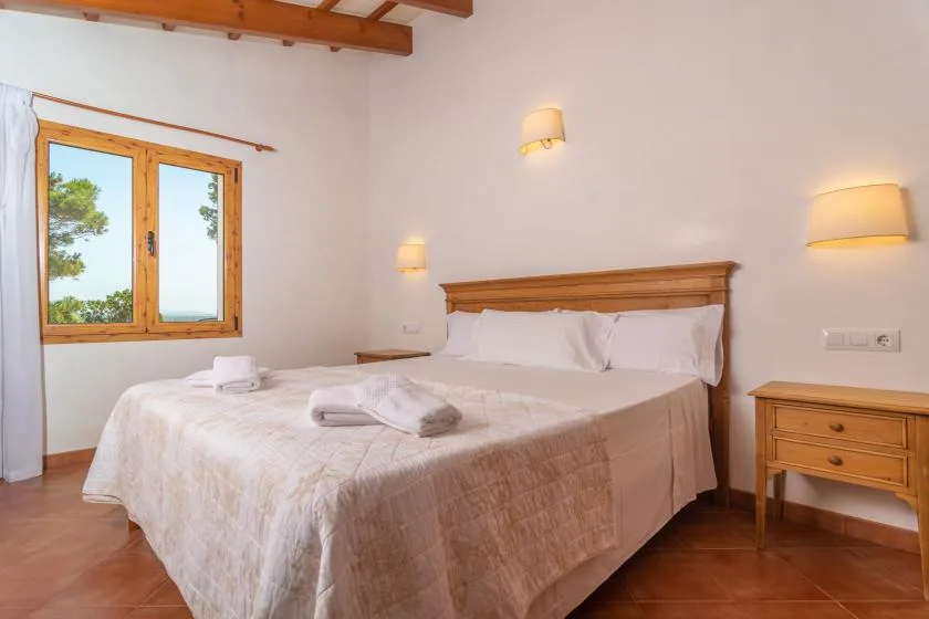 Un dormitorio con una cama doble, cabecero de madera y ventana.