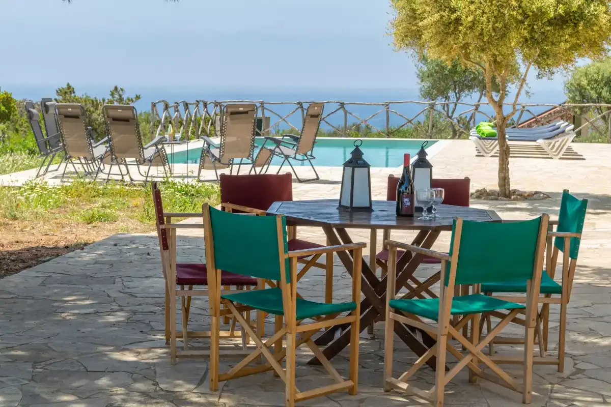 Una zona de comedor al aire libre da a una piscina y al mar.