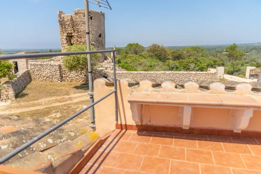 Una terraza en la azotea con baldosas mira hacia ruinas de piedra y un paisaje verde.