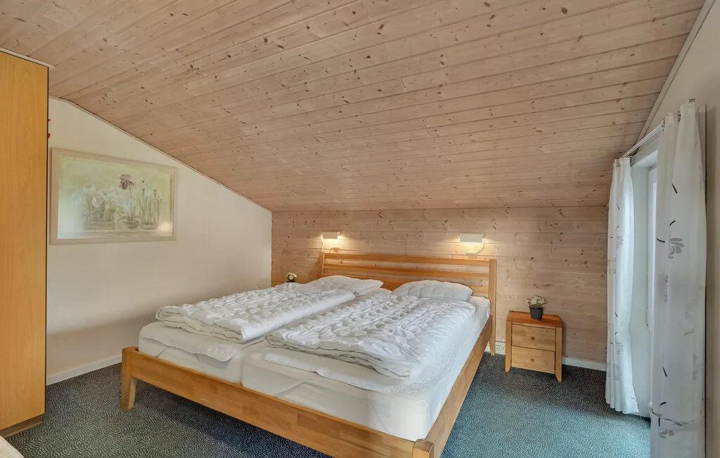 Un dormitorio con dos camas bajo un techo inclinado revestido de madera.