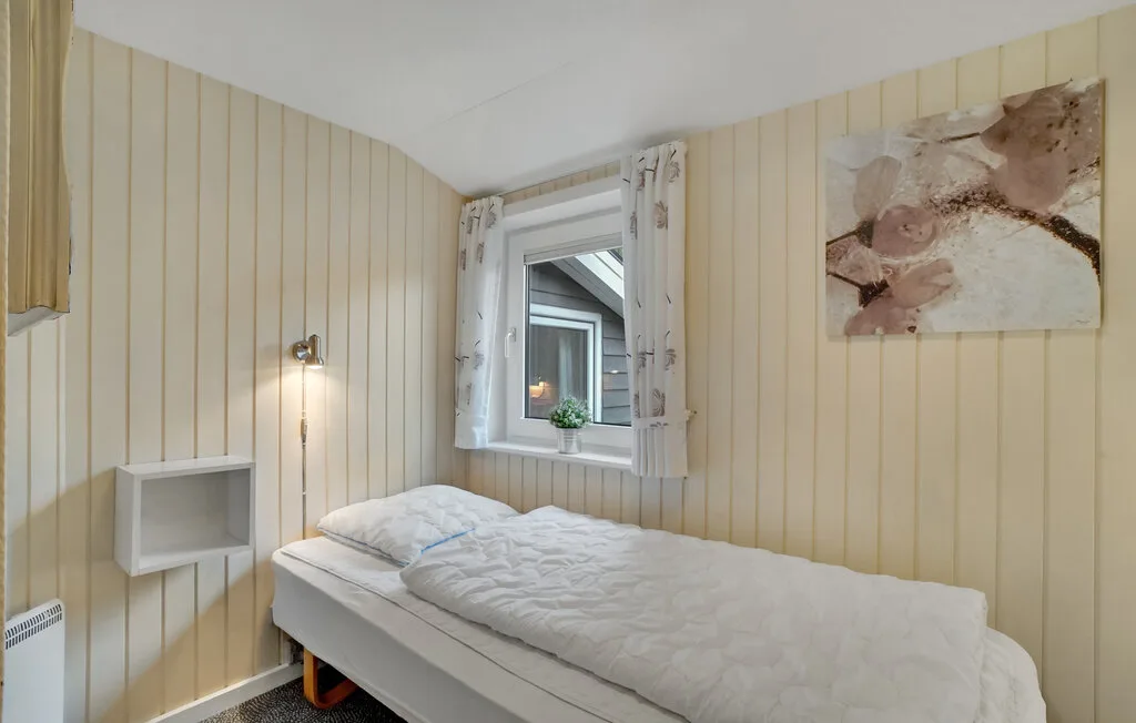 Un dormitorio con una cama debajo de una ventana.