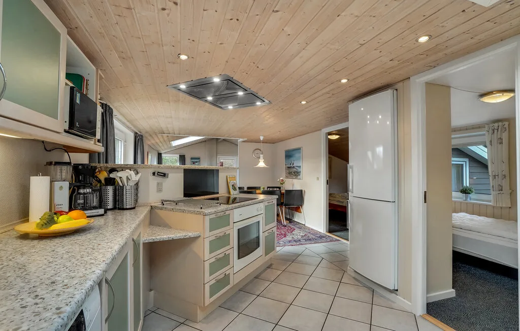 Una cocina compacta con muebles claros y una encimera se abre a un dormitorio.