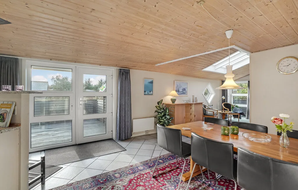 Comedor con una mesa de madera, asientos y ventanas grandes.