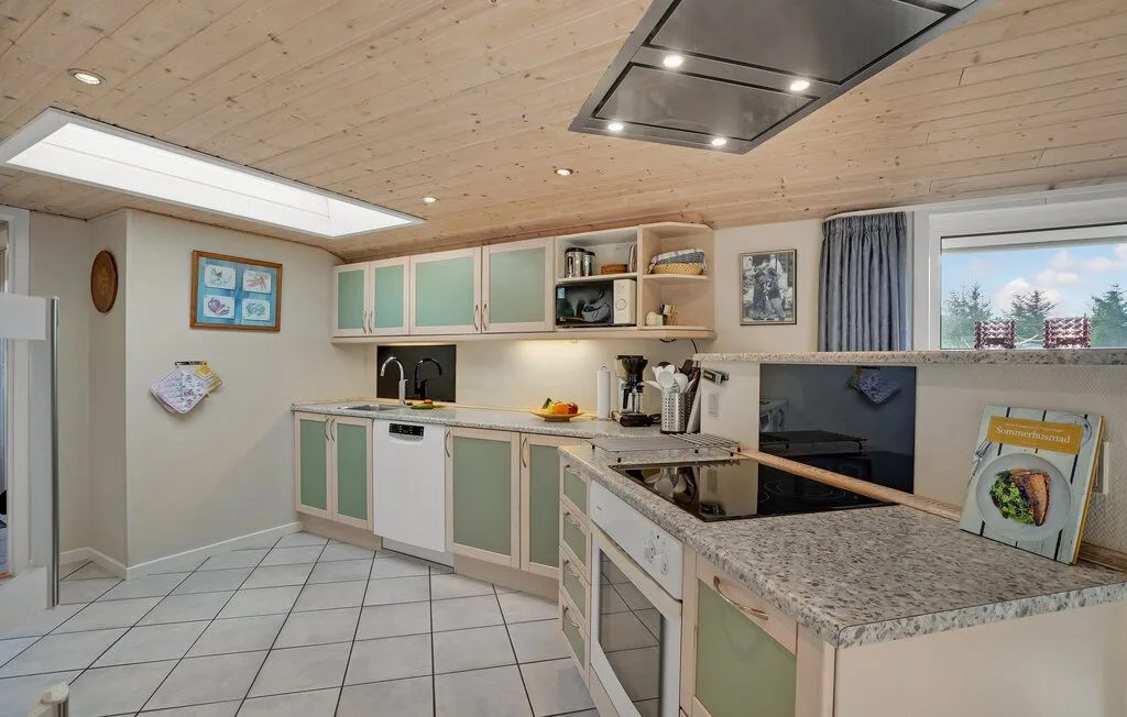 Una cocina con gabinetes claros, piso de baldosas e isla central.