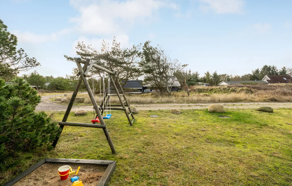 Una zona de juegos al aire libre con columpios de madera junto a un arenero.