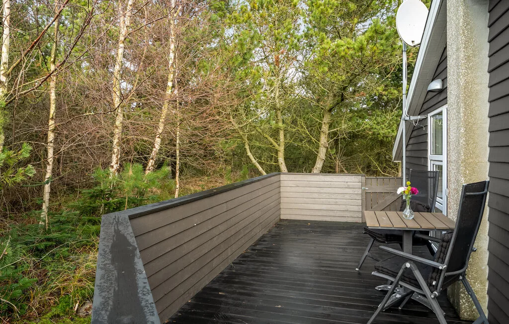 Una terraza exterior con asientos da a una zona arbolada.