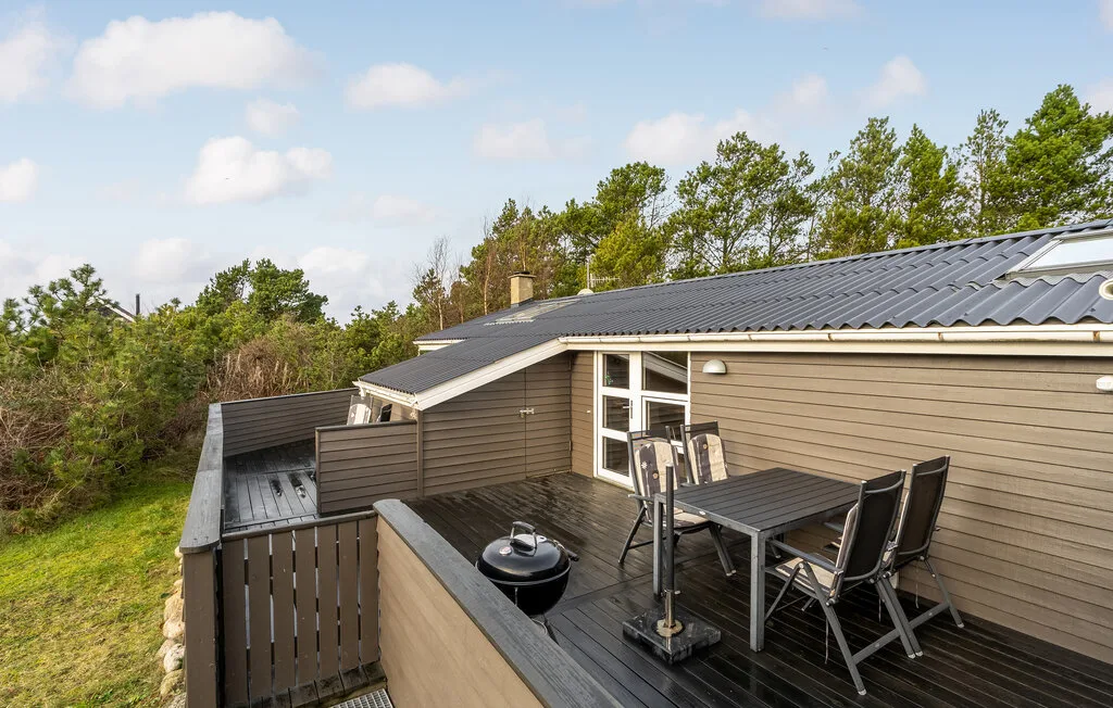 Una terraza exterior con una mesa de comedor y sillas junto a una casa.