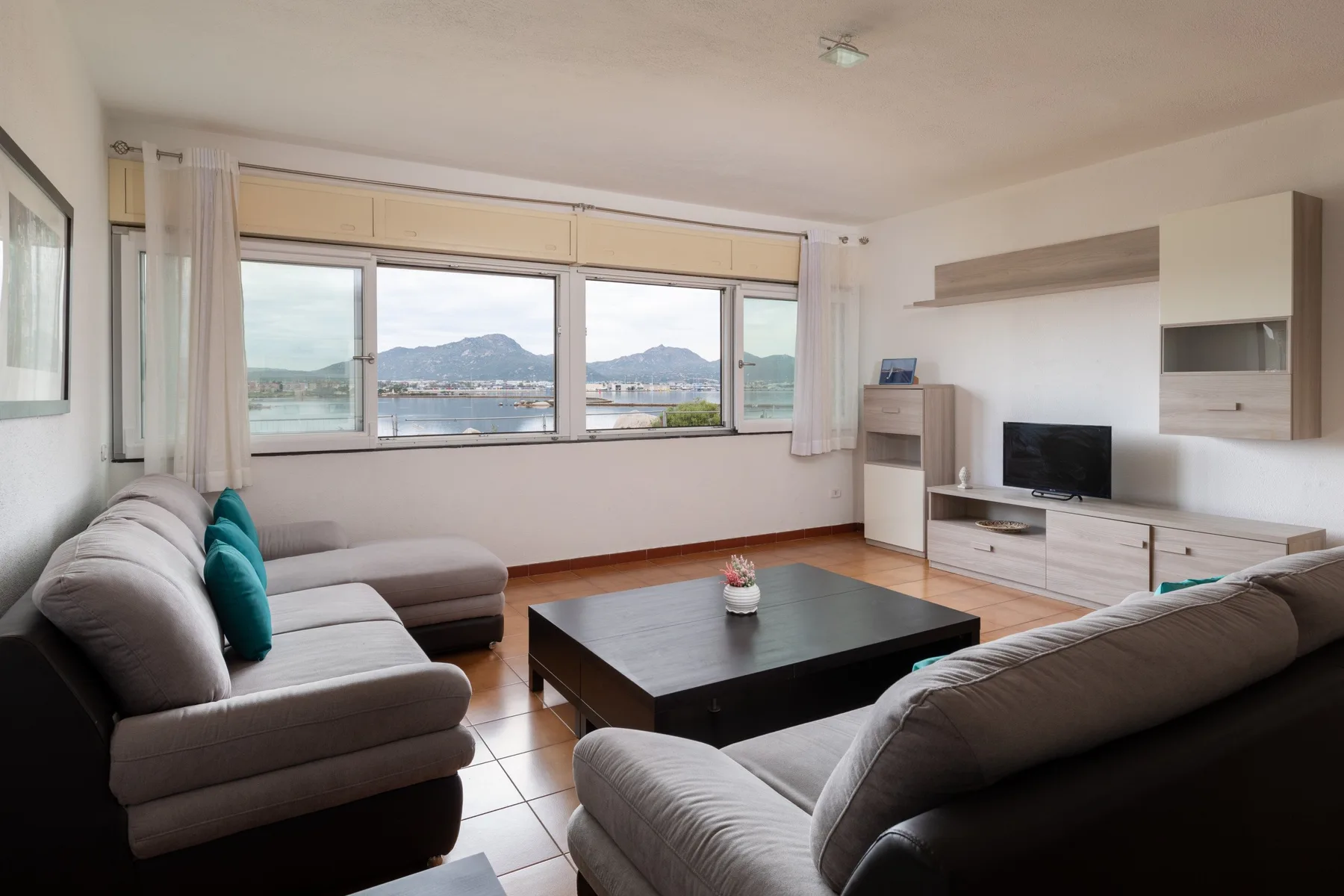 Una sala de estar con sofás, una mesa de centro y grandes ventanas con vistas al agua.