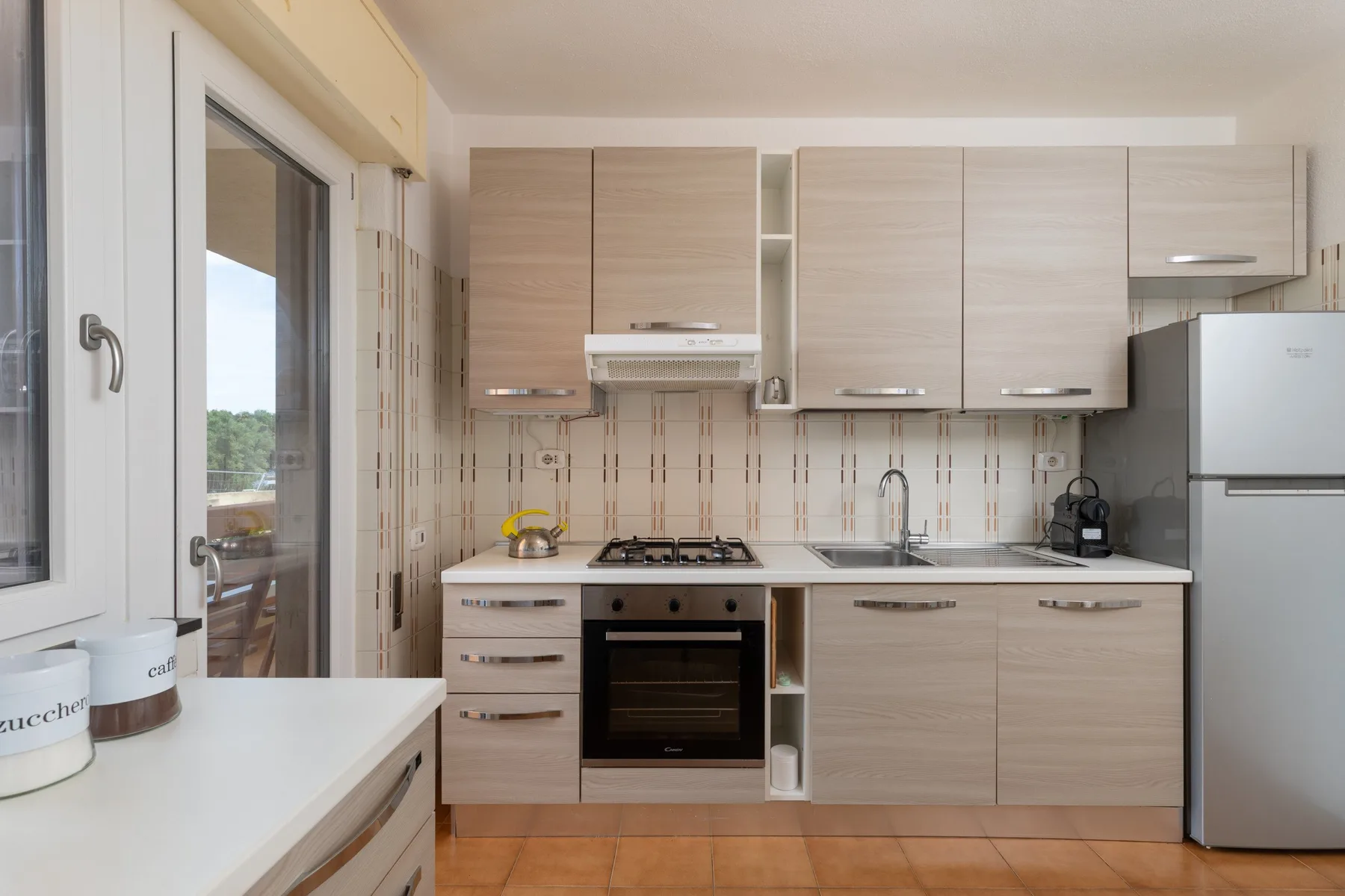 Una cocina luminosa con gabinetes de madera clara, una estufa y un refrigerador.