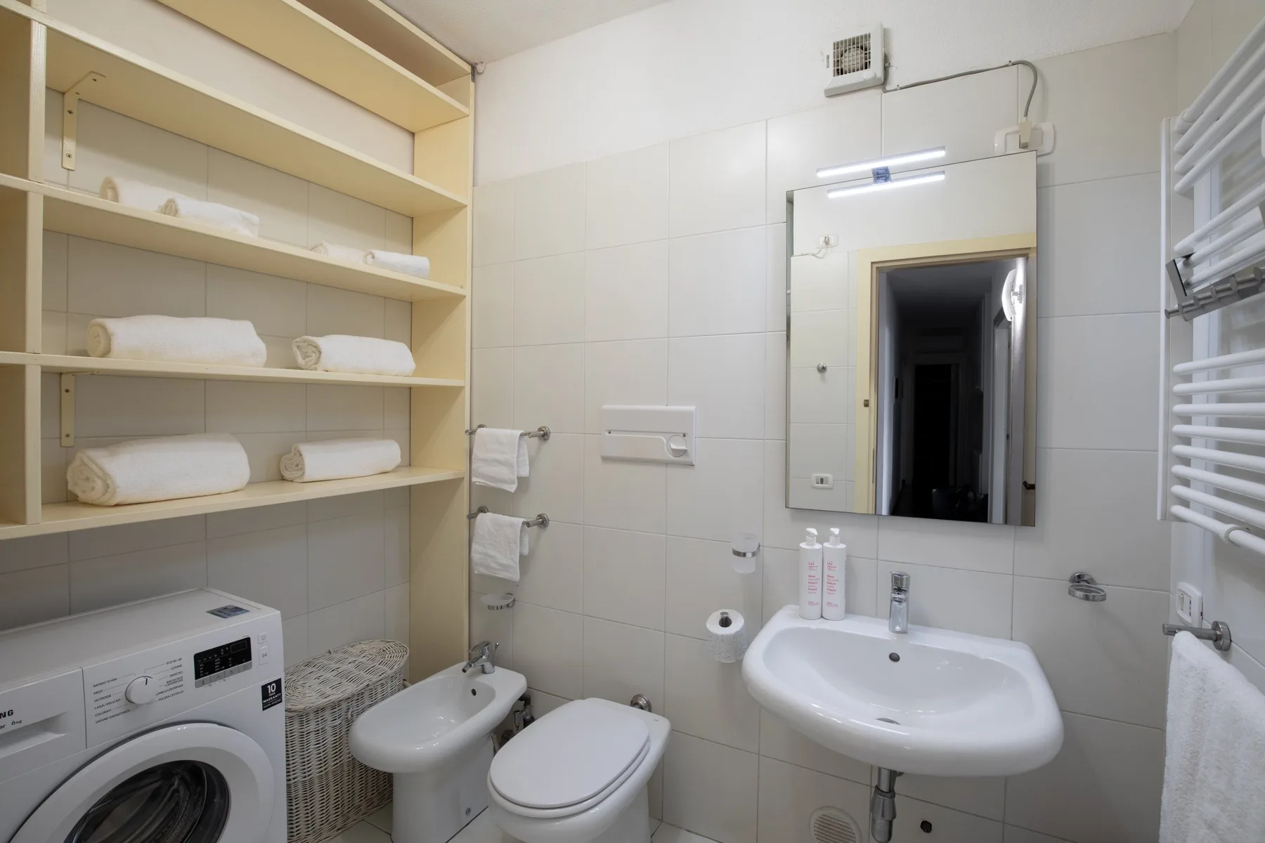 Un baño de azulejos con lavabo, inodoro y lavadora.