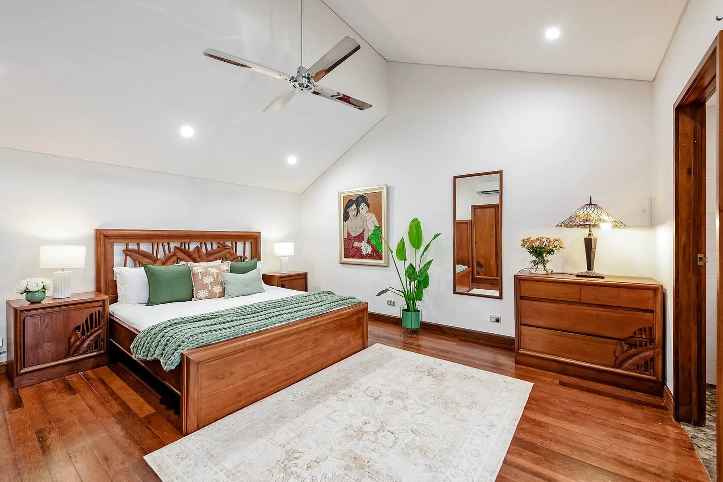 Dormitorio con cama de madera, ropa de cama verde y una alfombra clara.