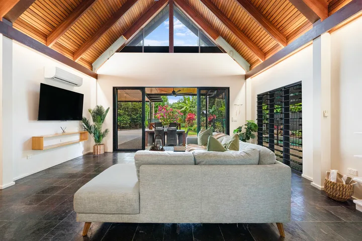 Una sala luminosa con techo alto de madera y asientos frente a un jardín.