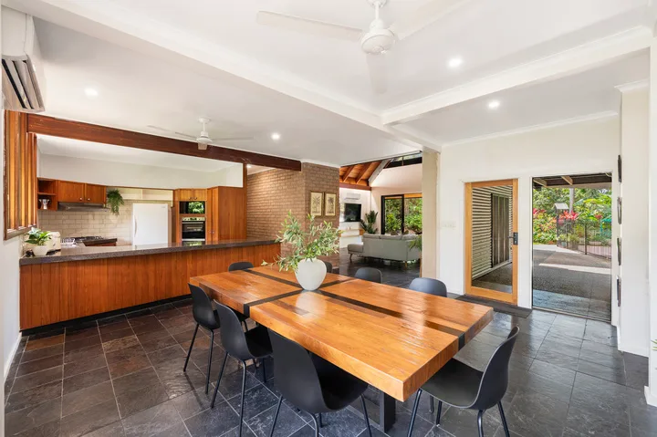 Un comedor y cocina de planta abierta con una mesa de madera y asientos oscuros.