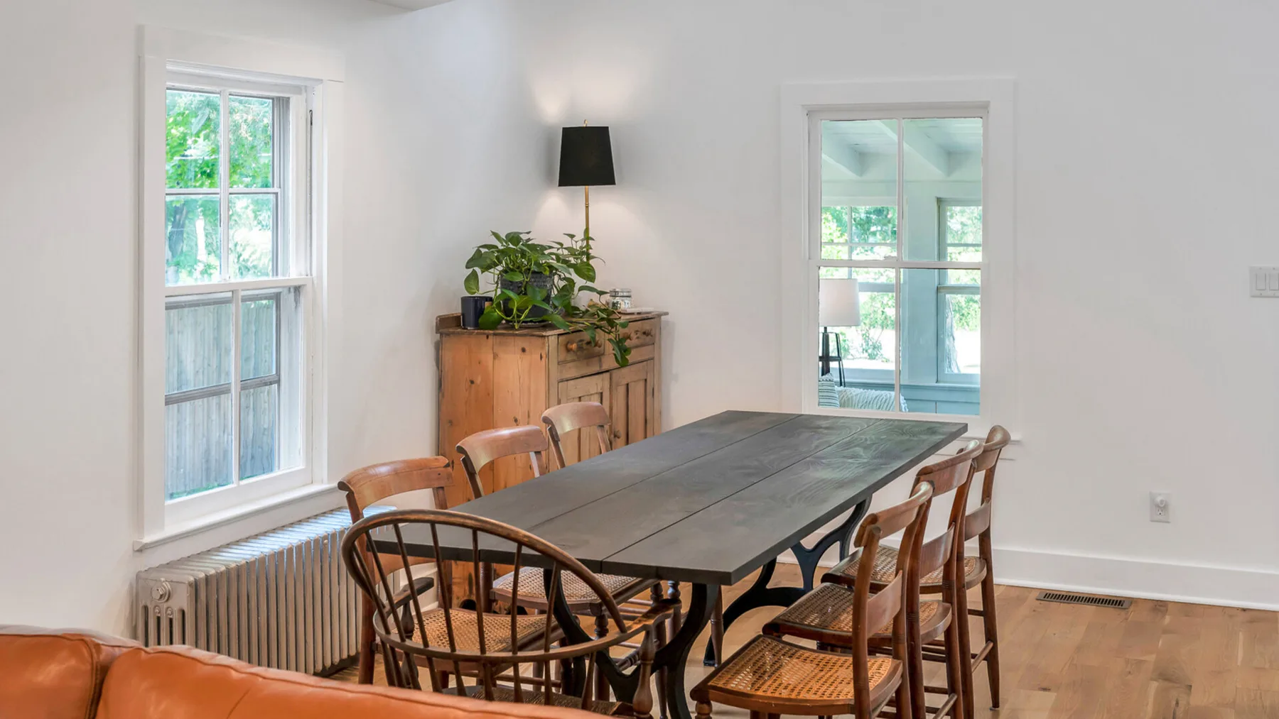 Un comedor con una mesa larga y asientos de madera junto a ventanas grandes.