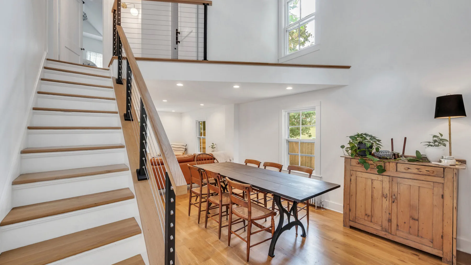 Comedor abierto con una mesa larga junto a una escalera.