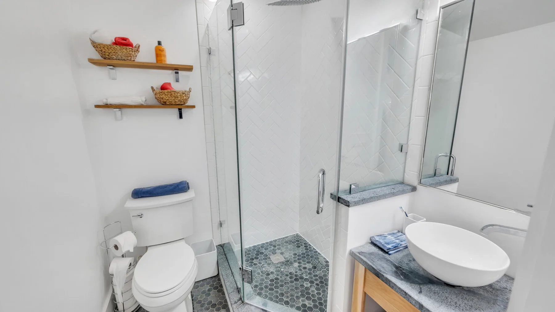 Un baño luminoso con una ducha de vidrio y un lavabo sobre mueble.