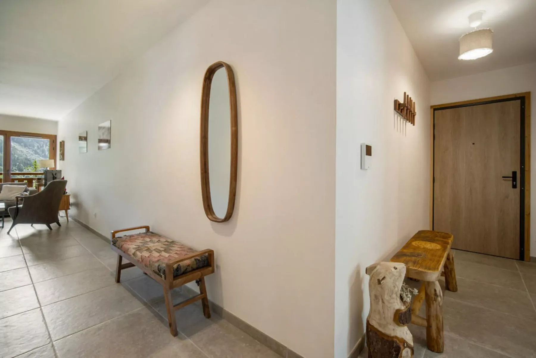 A bright entry hall with a wooden front door and a bench along the wall.