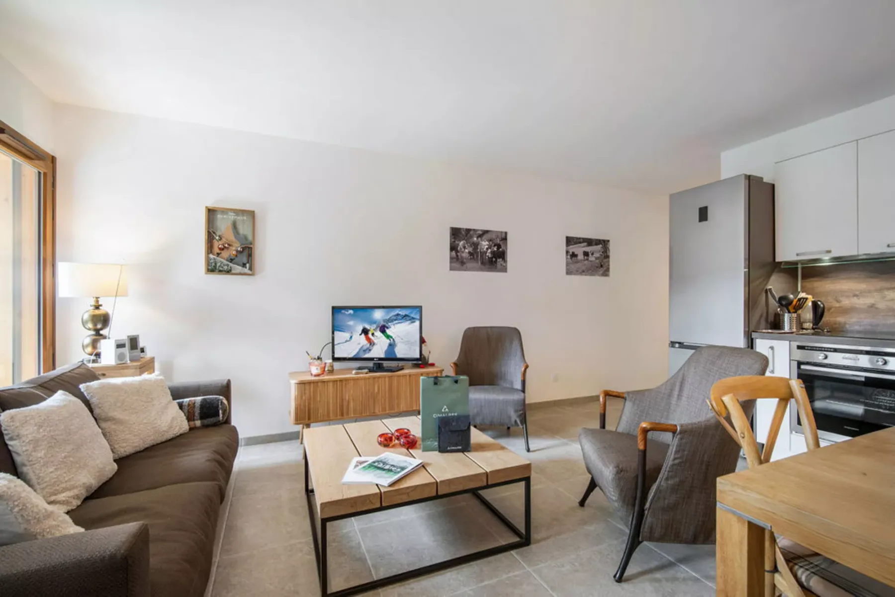 A living room with seating, a coffee table, and an open kitchen.
