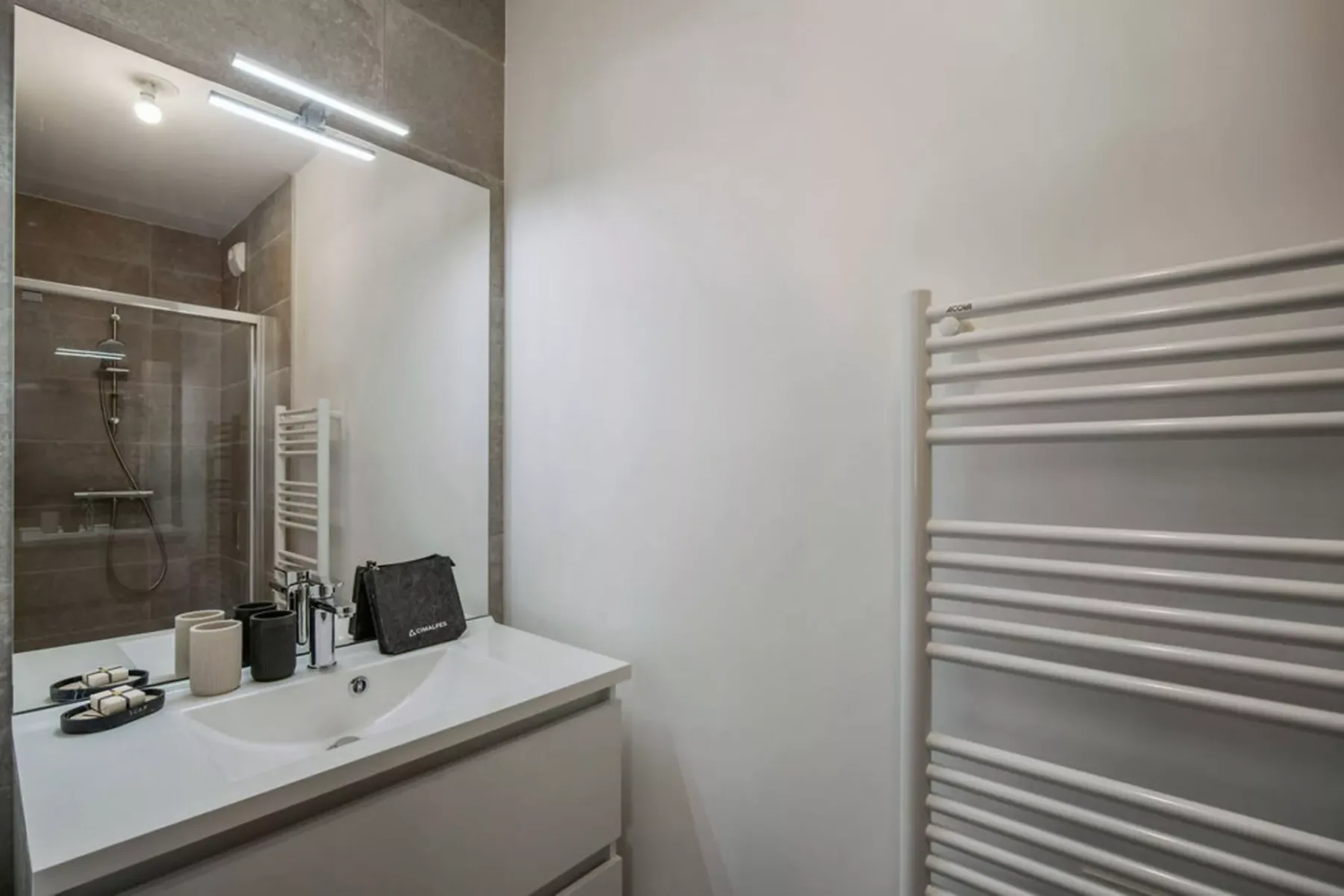 A bathroom vanity with a mirror and a wall-mounted towel warmer.