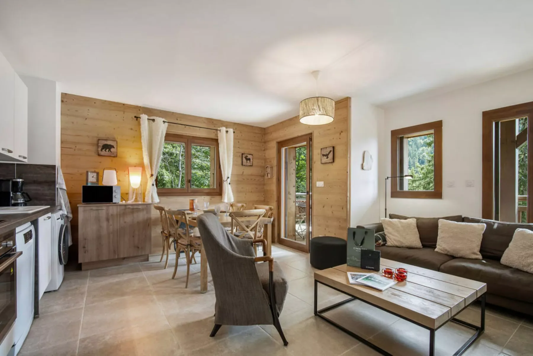 A bright open-plan living and dining area with a kitchen and large windows.