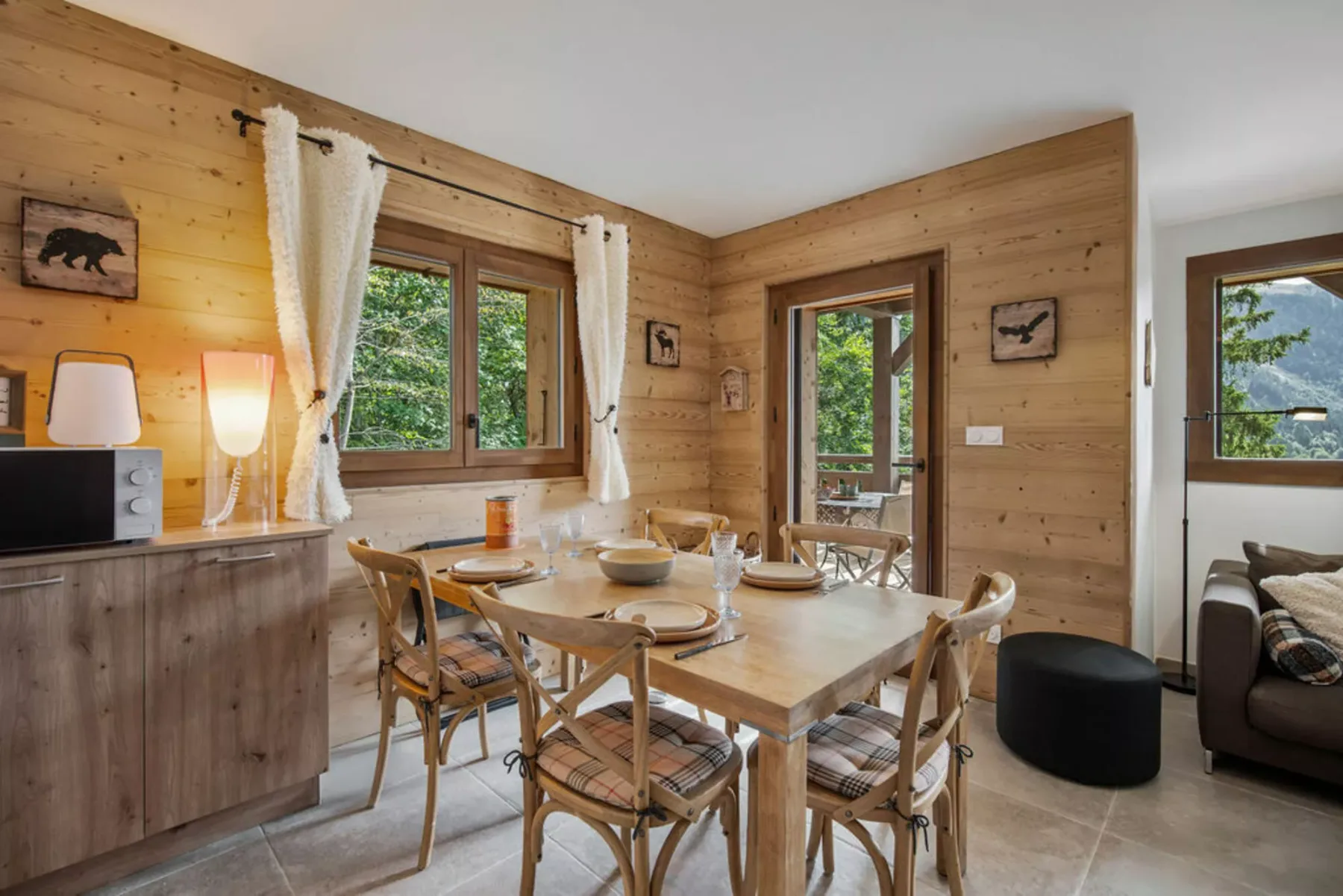 A wood-paneled dining area with a table and seating beside a large window.