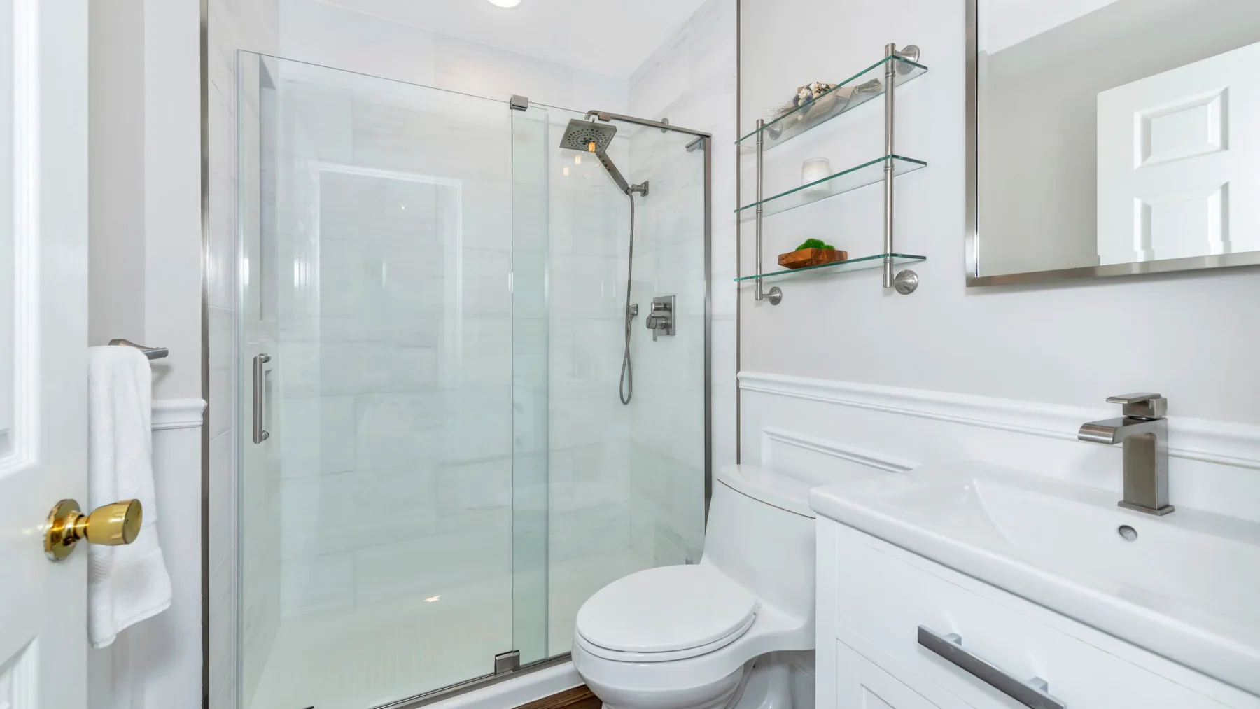 Un baño luminoso con ducha de vidrio y tocador blanco.