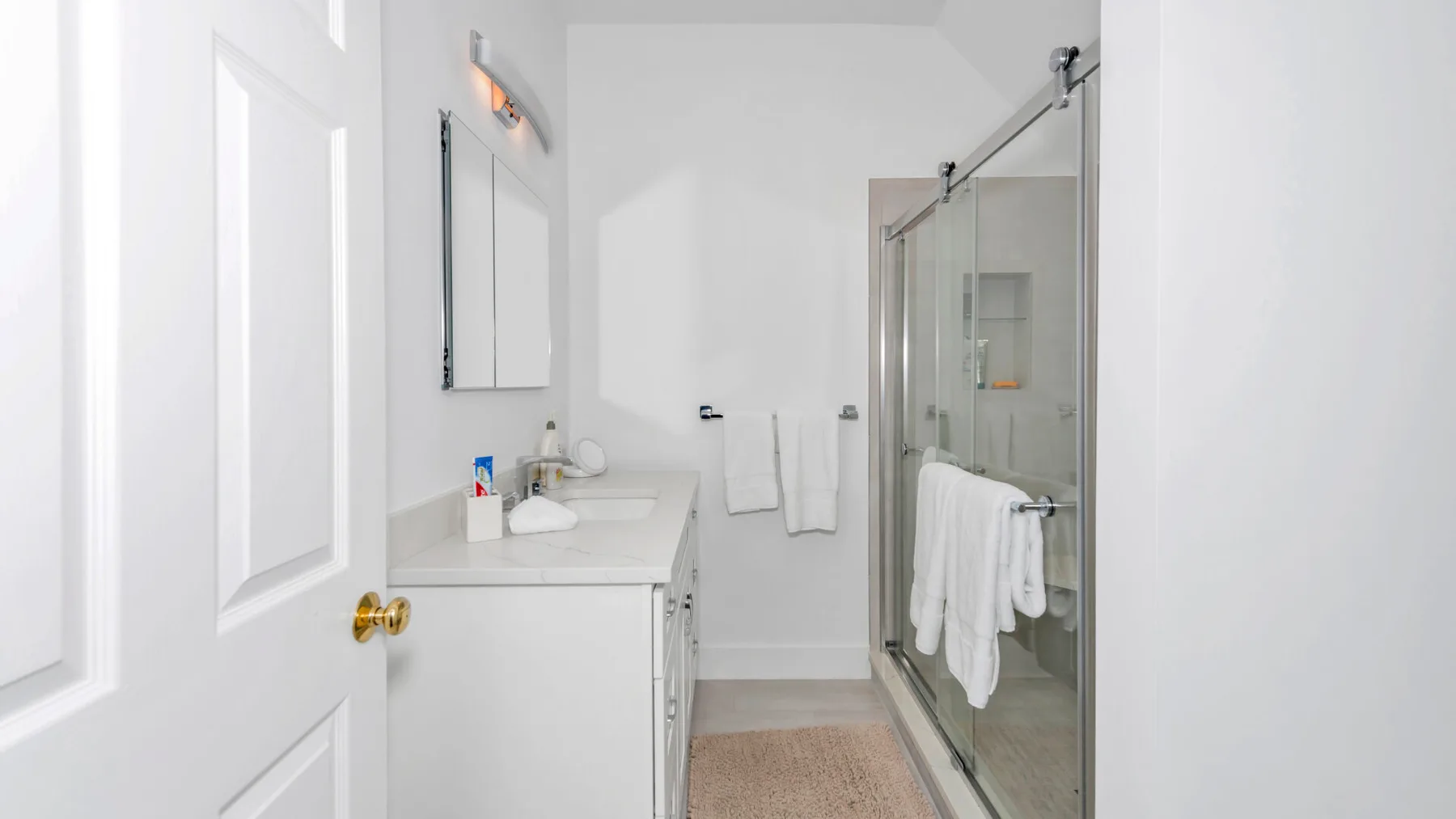 Un baño luminoso con lavabo y ducha de cristal.
