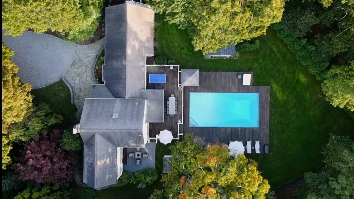 Una vista aérea muestra una casa, una piscina y árboles alrededor.