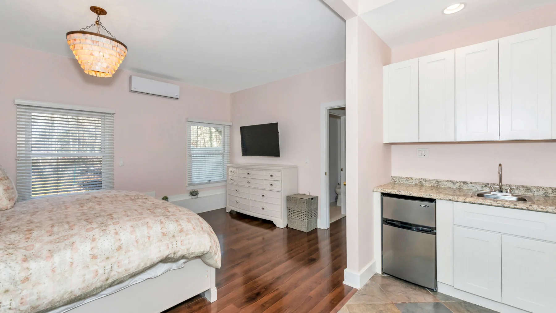Un dormitorio con una cama y una pequeña cocina junto a la pared derecha.