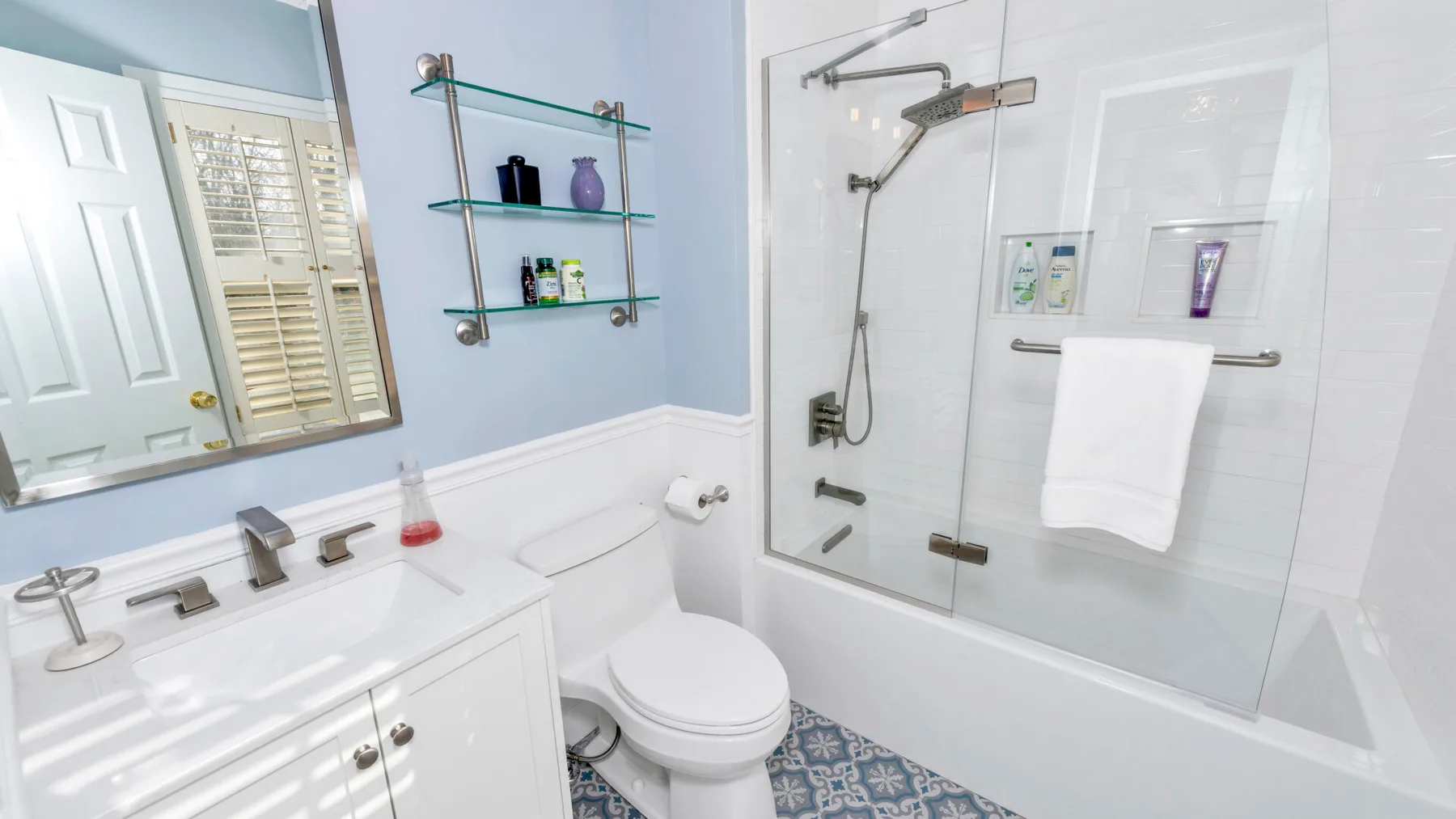 Un baño luminoso con lavabo, inodoro y ducha con mampara de vidrio.