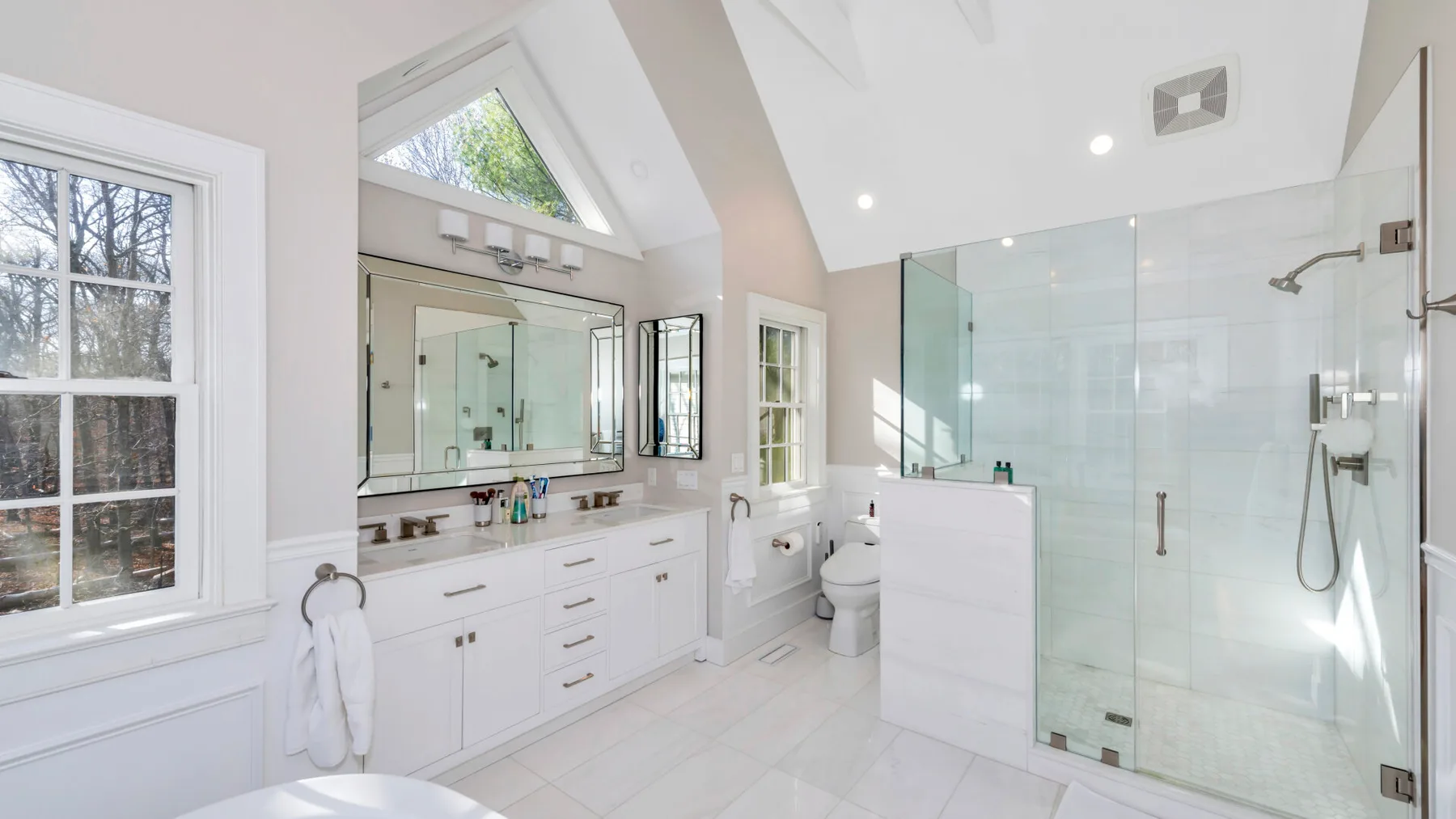 Un baño luminoso con tocador de doble lavabo y ducha de vidrio.