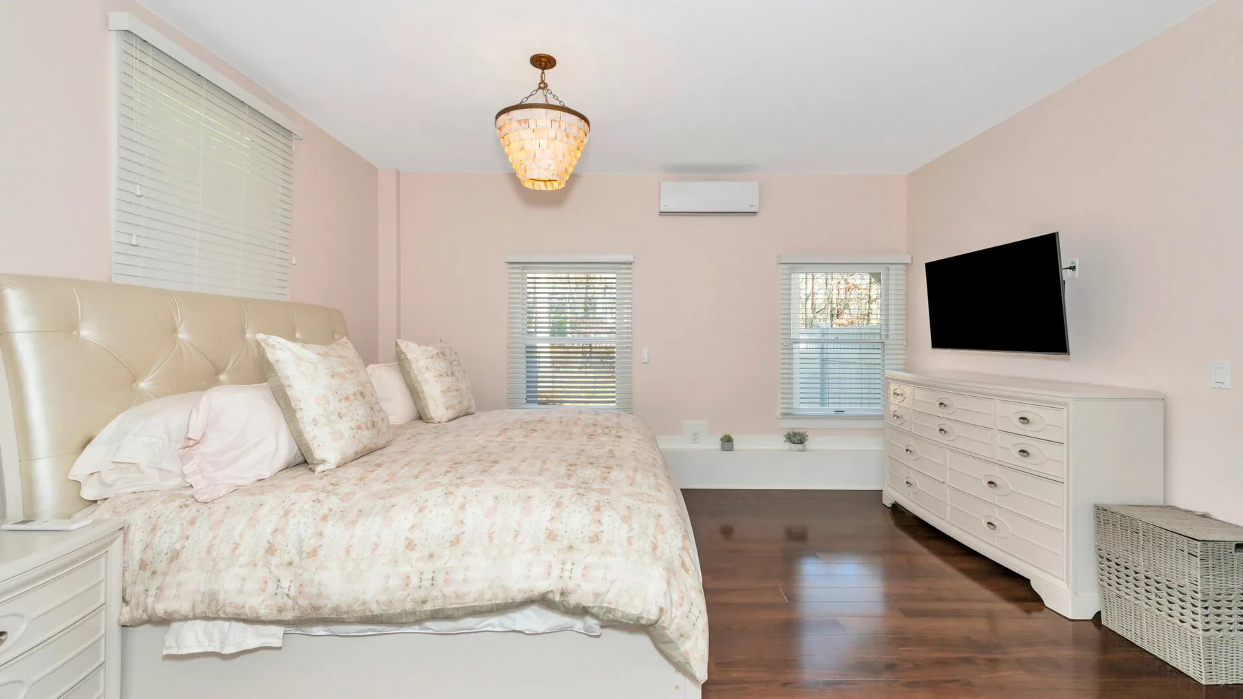 Un dormitorio con una cama grande, una cómoda blanca y ventanas.