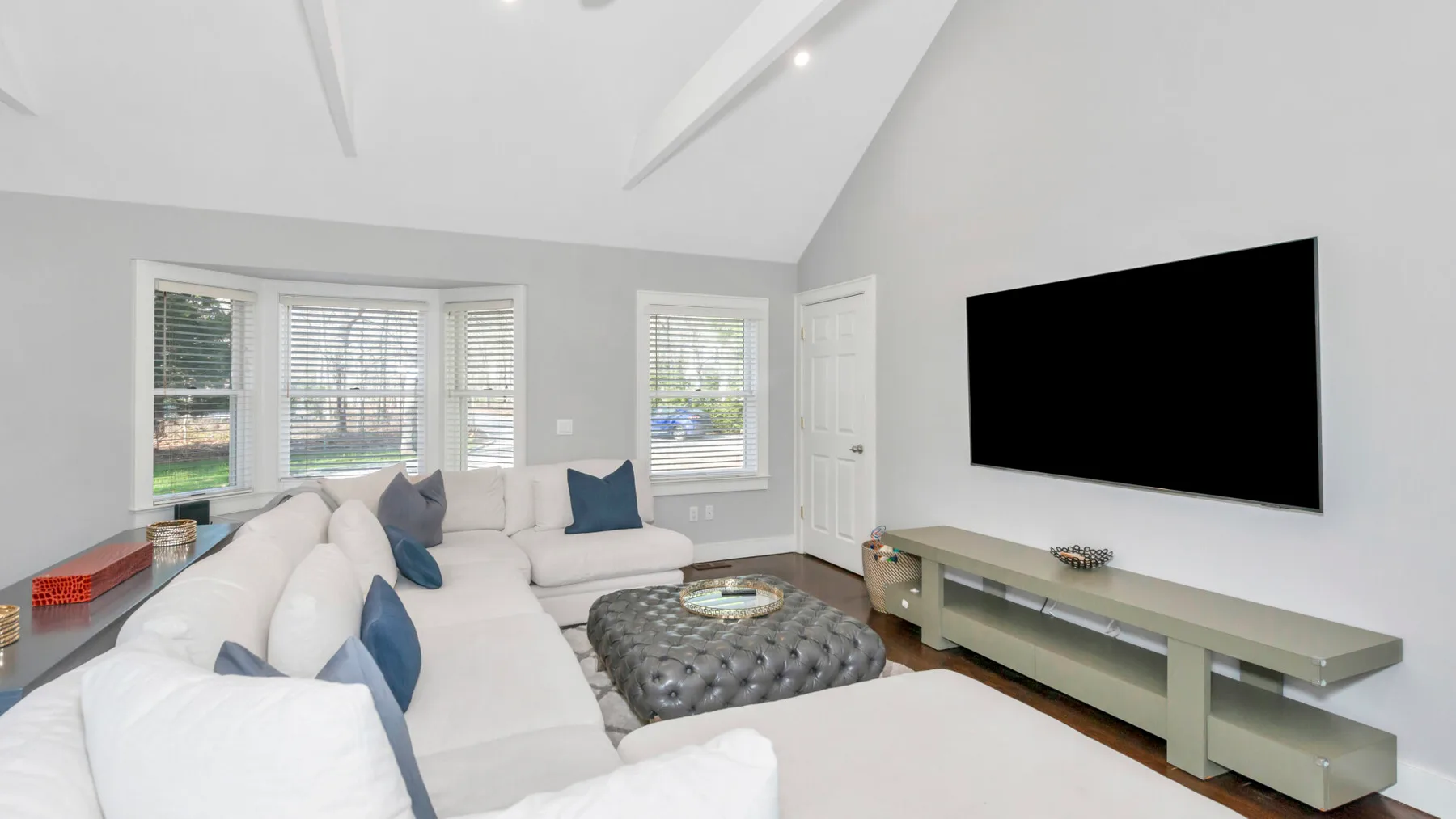 Una sala luminosa con asientos claros, un televisor y ventanas.