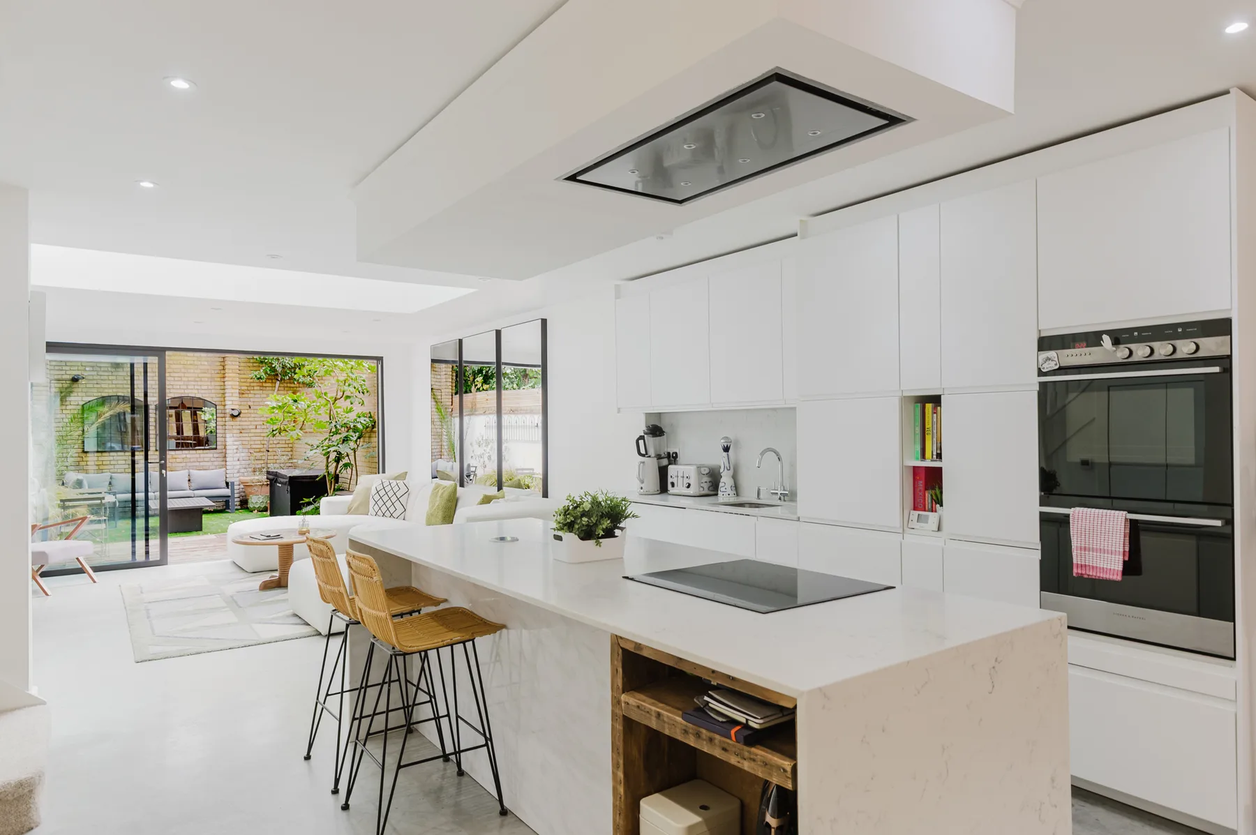 A bright kitchen with a long island and dining seating beside large windows.