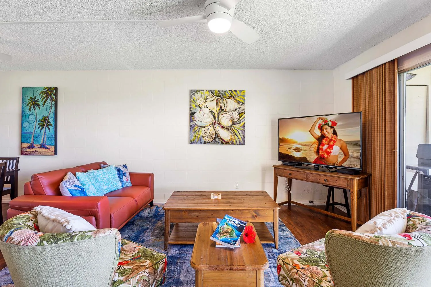 Una sala de estar con asientos alrededor de mesas de madera y un televisor.
