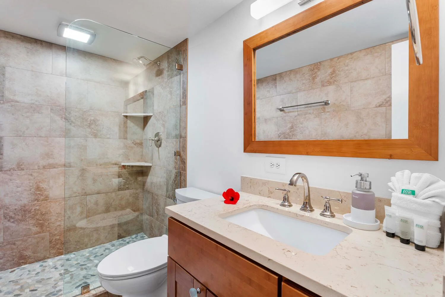 Un baño alicatado con ducha de vidrio, inodoro y lavabo.