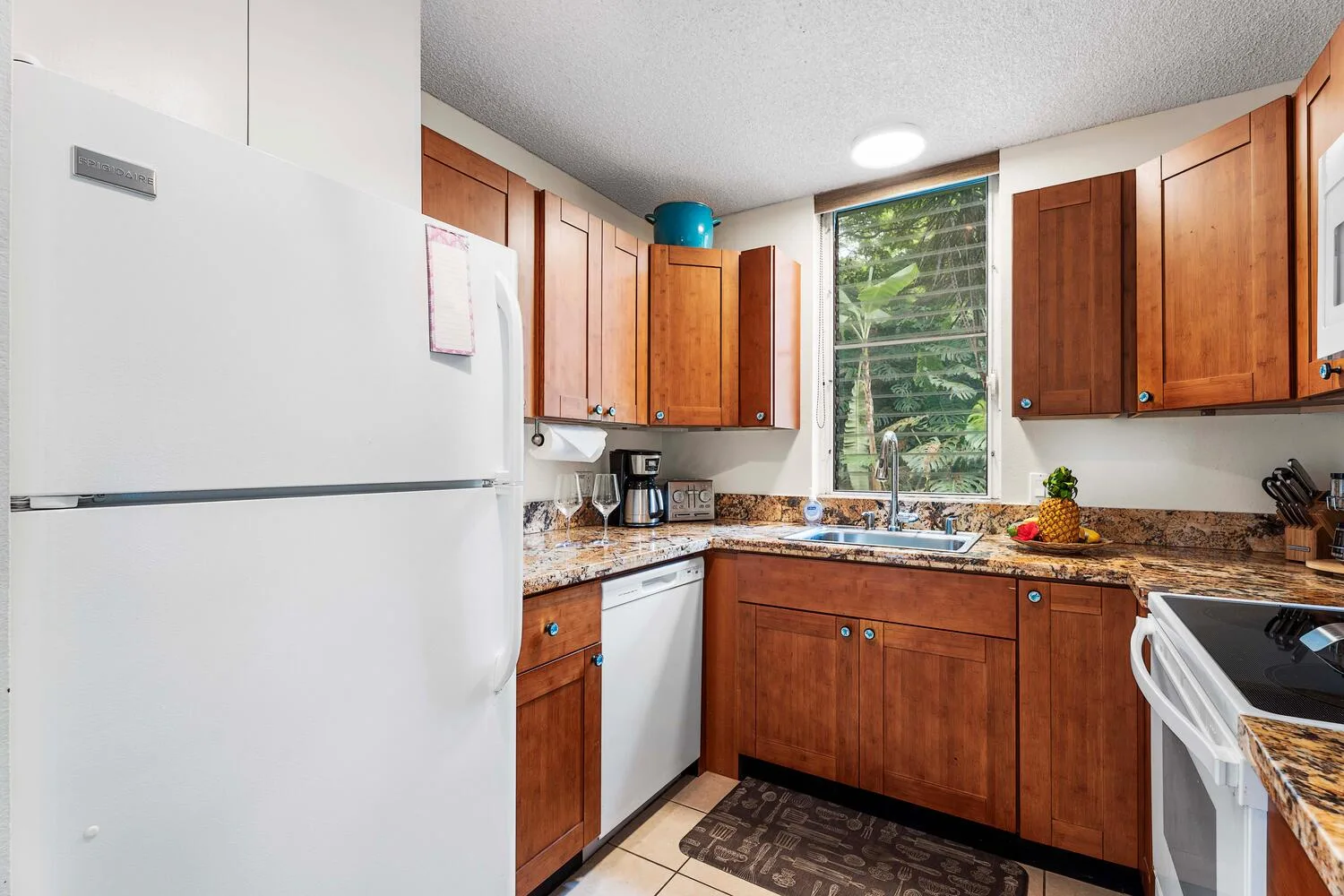 Una cocina con gabinetes de madera, un refrigerador y una ventana sobre el fregadero.
