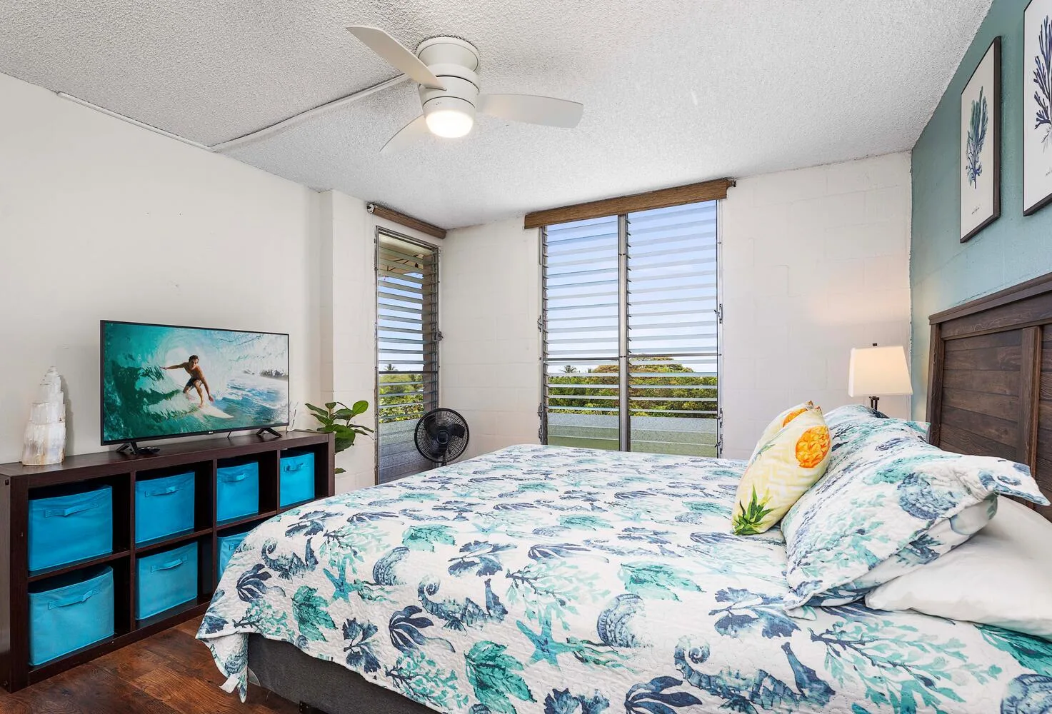 Un dormitorio con una cama cubierta con ropa de cama floral azul y verde.