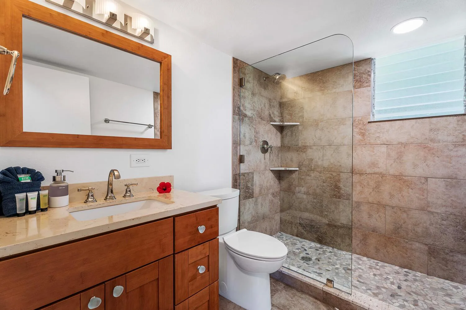Un baño con lavabo, espejo y ducha con mampara de vidrio.