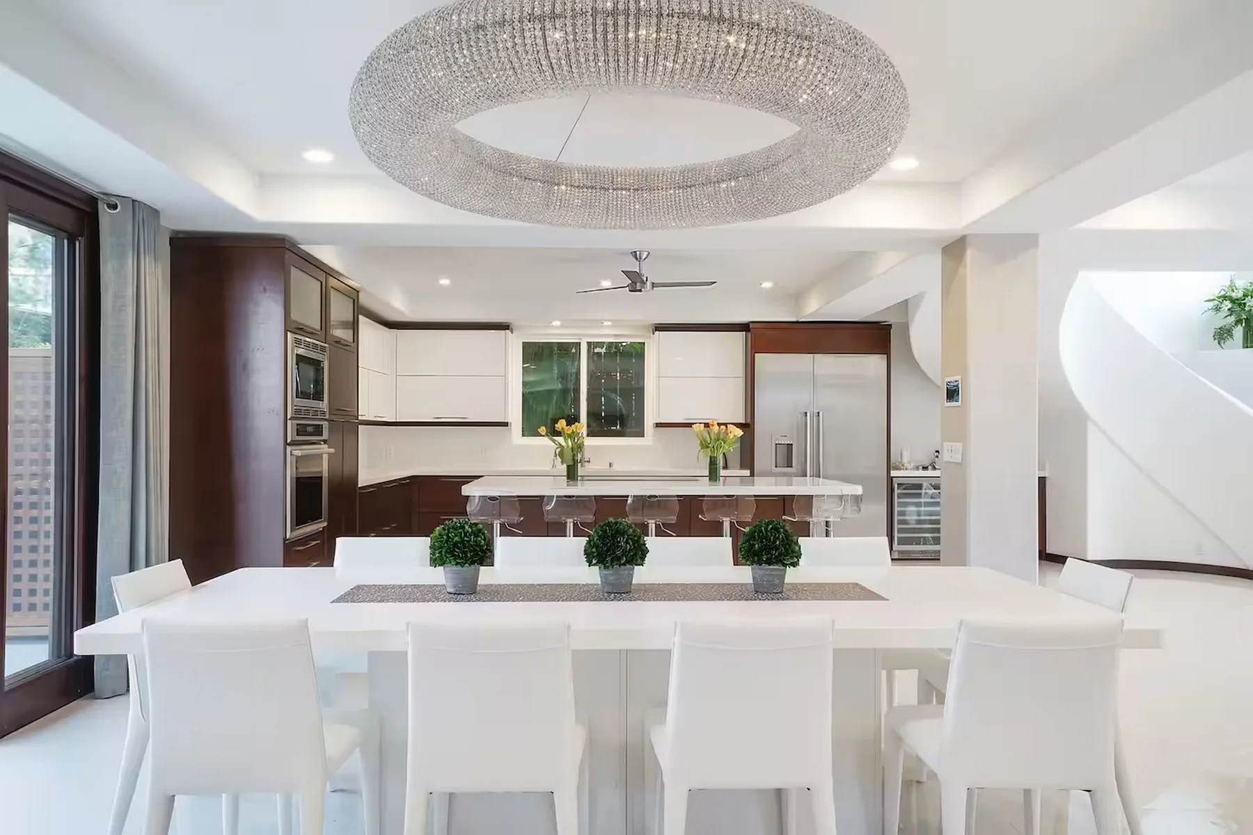 Una cocina luminosa con comedor, una mesa larga blanca y armarios modernos.